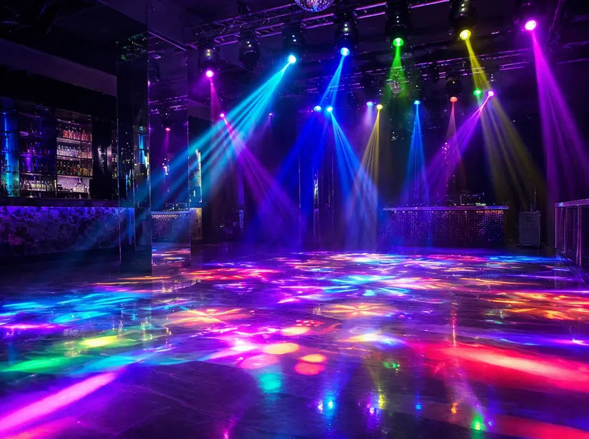 Dance floor DJ lights installed above a commercial nightclub dance floor, firing colored beams downward across the floor plane