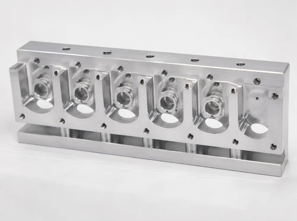 CNC-machined aluminum diode mounting block showing precision-bored seats for laser diodes