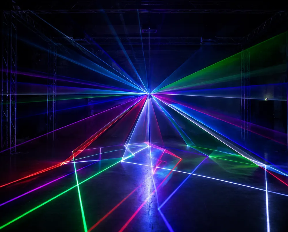 Disco DJ laser lights unit projecting multi-color geometric patterns across a dark venue