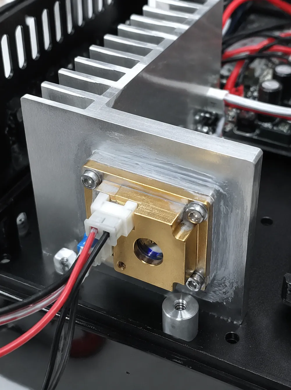 Close-up of laser diode thermal interface with heatsink fins and thermal compound application on DJ laser light assembly