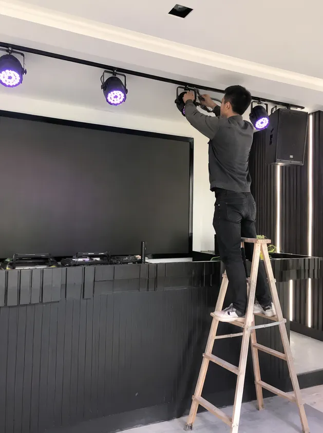 AV contractor installing fixed DJ booth lighting as part of venue fit-out project