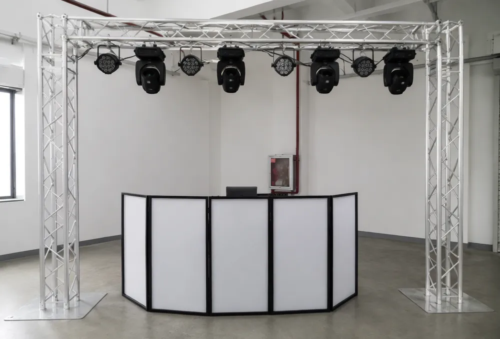 Aluminum DJ lighting truss stand with horizontal span and vertical columns supporting multiple lighting fixtures above a DJ booth