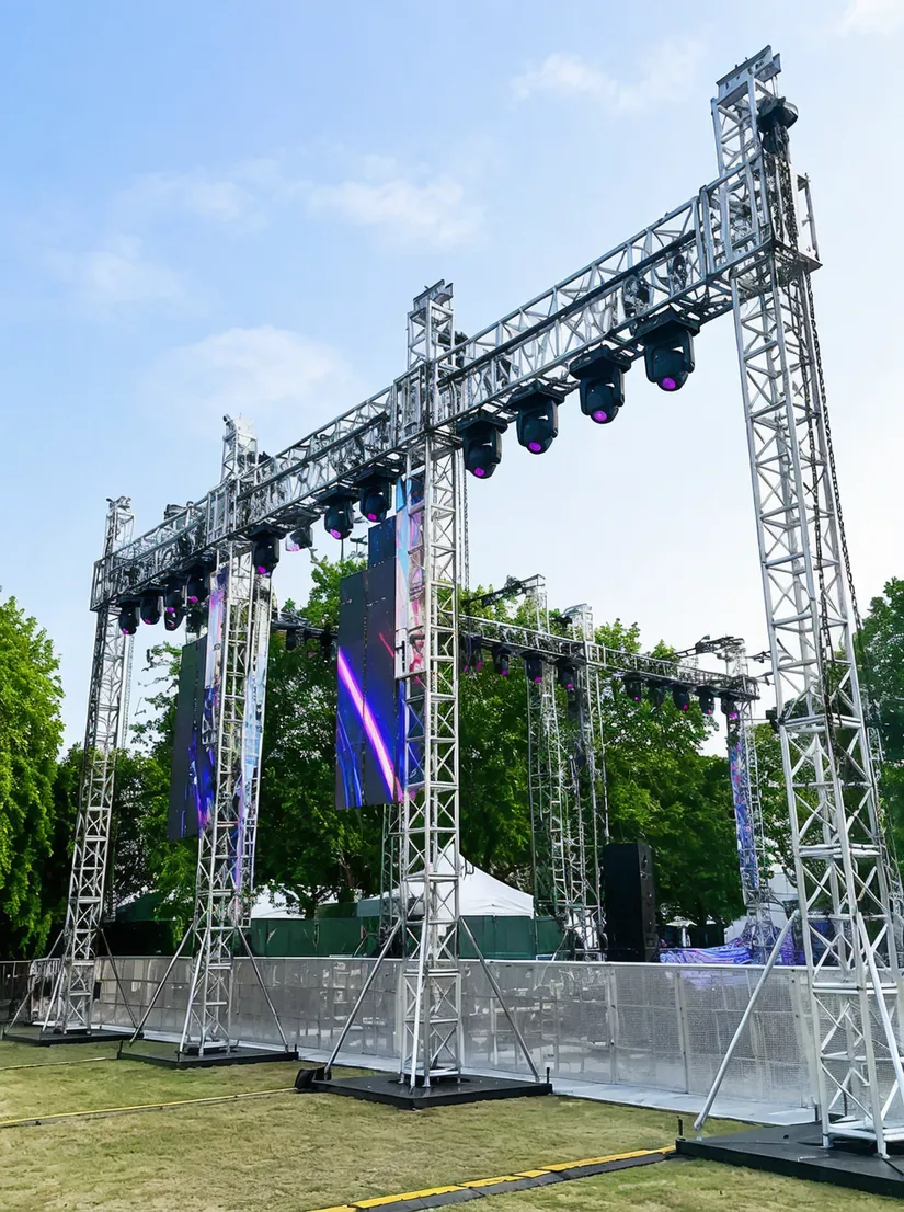 Heavy-duty truss stands deployed at outdoor festival with multiple fixtures and LED panels mounted per span
