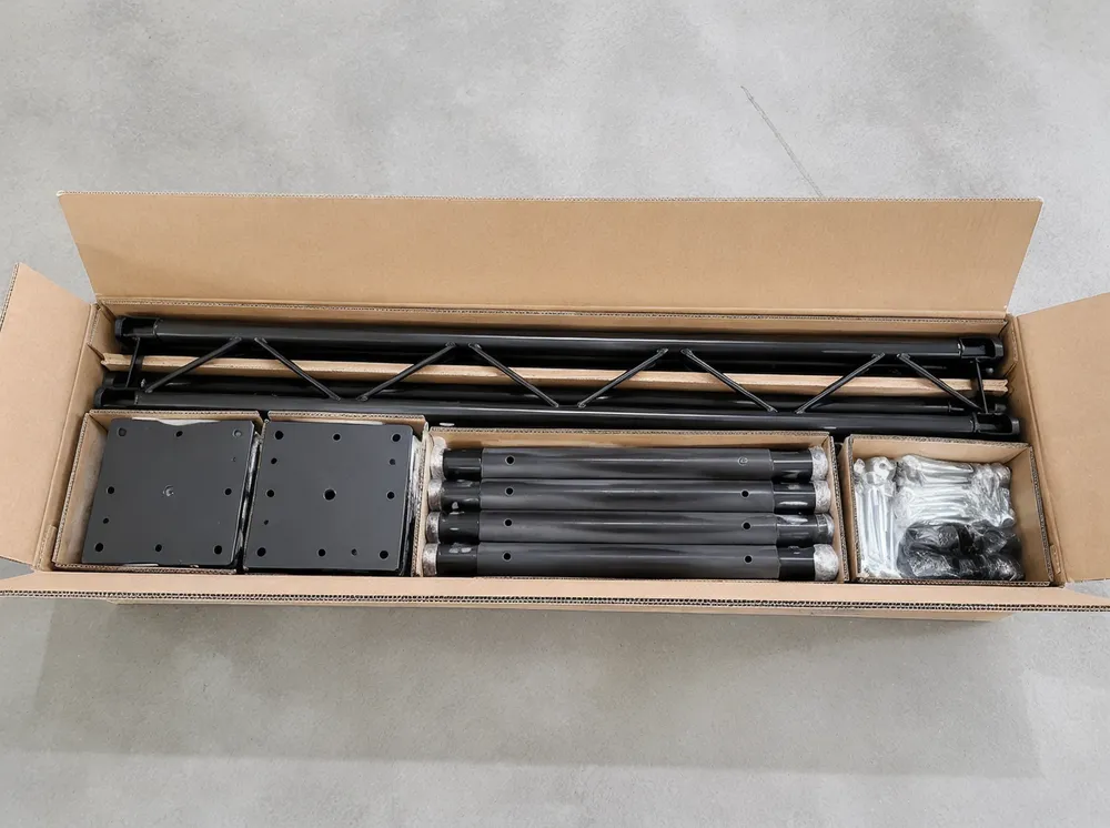 Truss stand knocked-down packaging showing separated columns, span, base plates, and hardware in nested master carton