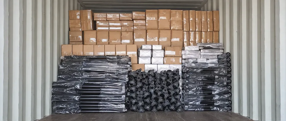 Knocked-down DJ light stands packed efficiently inside a shipping container with mixed fixture cartons