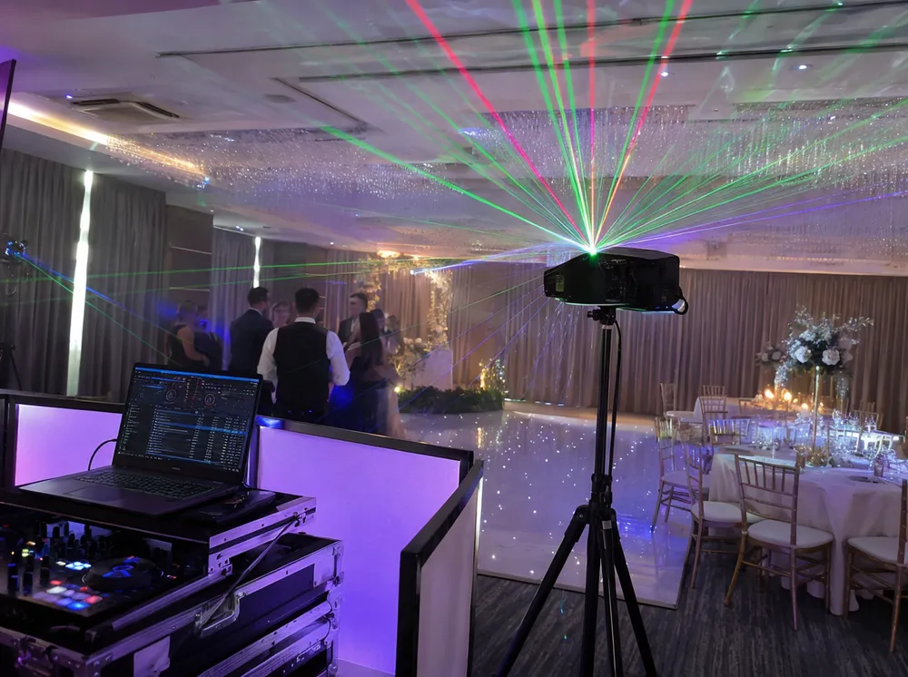 Mobile DJ laser projector setup at a wedding event with tripod mount