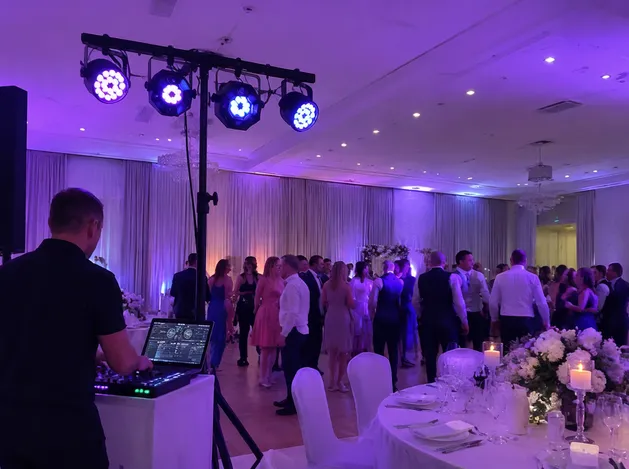 Mobile DJ using tripod-mounted party lights at a wedding reception event