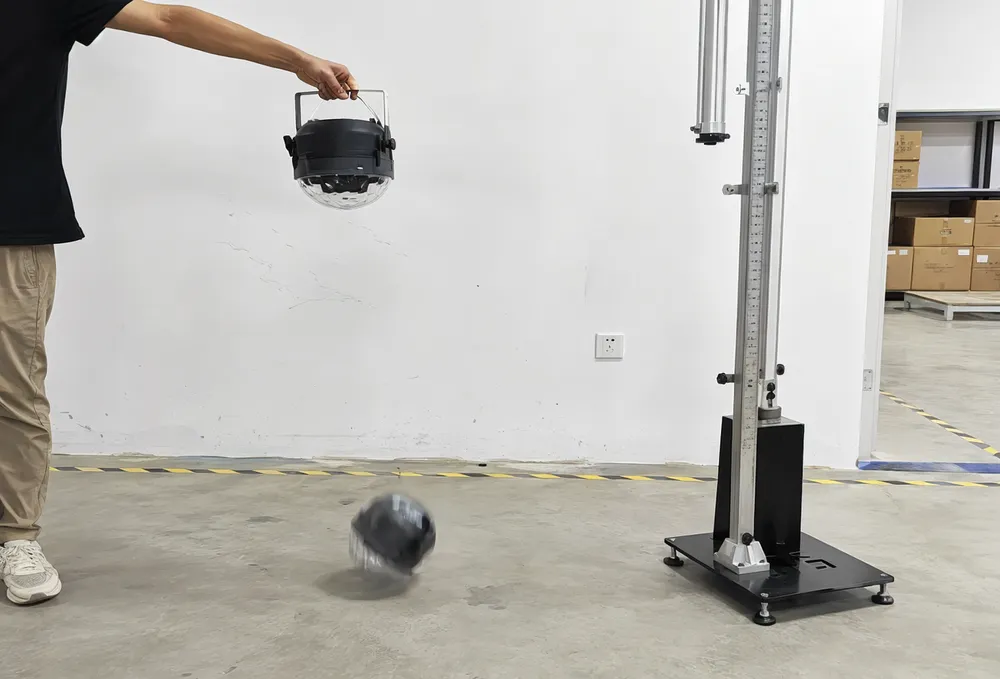 Portable DJ light undergoing drop testing on concrete surface — reinforced ABS housing design for rental fleet durability