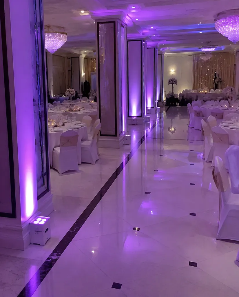 Wireless DJ uplights deployed across a banquet hall floor — cable-free event lighting setup