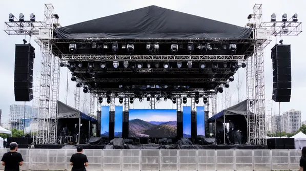 Outdoor festival stage with IP65-rated moving heads and wash fixtures in weather-exposed rigging