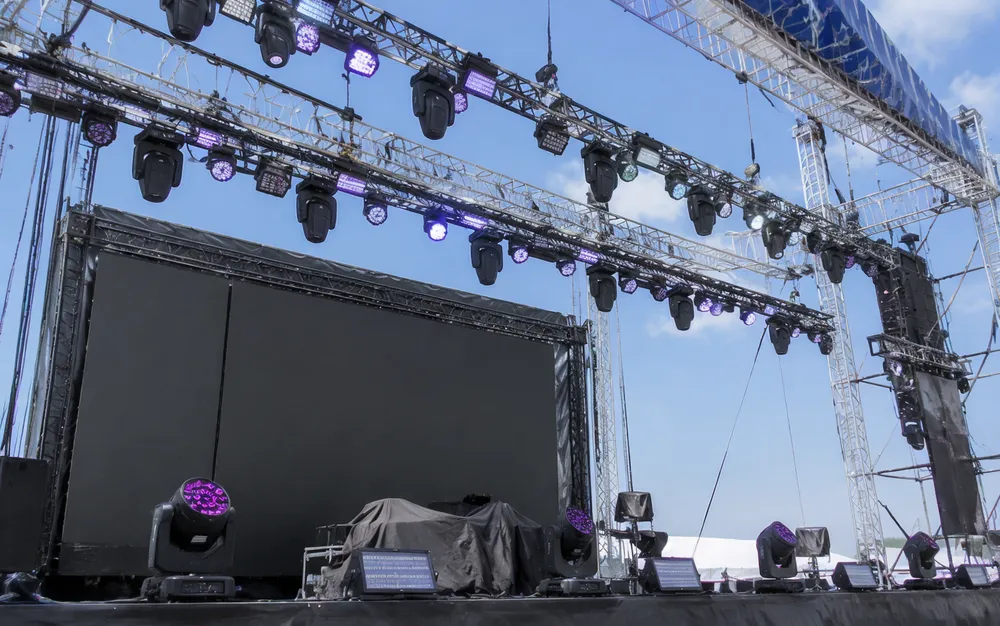 Concert stage lighting rig with moving heads and wash fixtures on truss at a live touring event