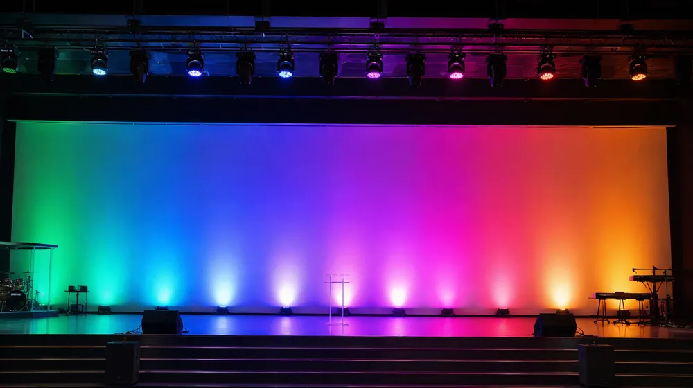 Wash moving head providing RGBW color wash coverage across a stage backdrop