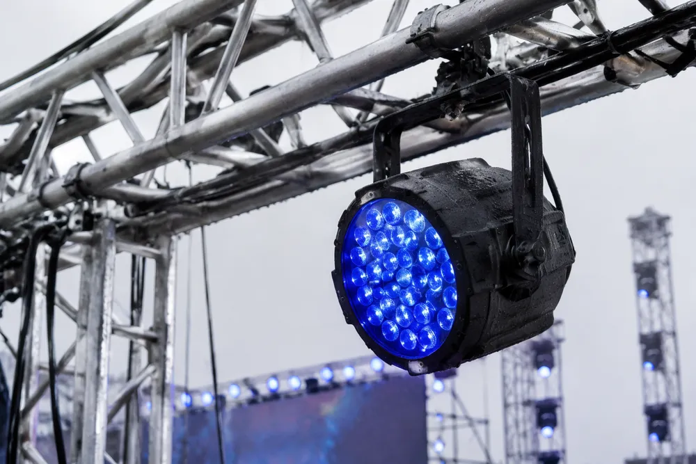 IP65-rated outdoor stage lighting fixture installed on festival truss rigging in rain conditions