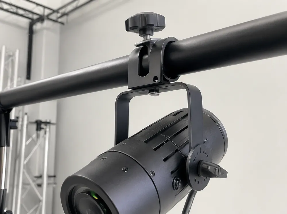 DJ spotlight universal clamp bracket mounted on 25mm-38mm T-bar showing thumb screw with captive washer and single quarter-turn tilt lock